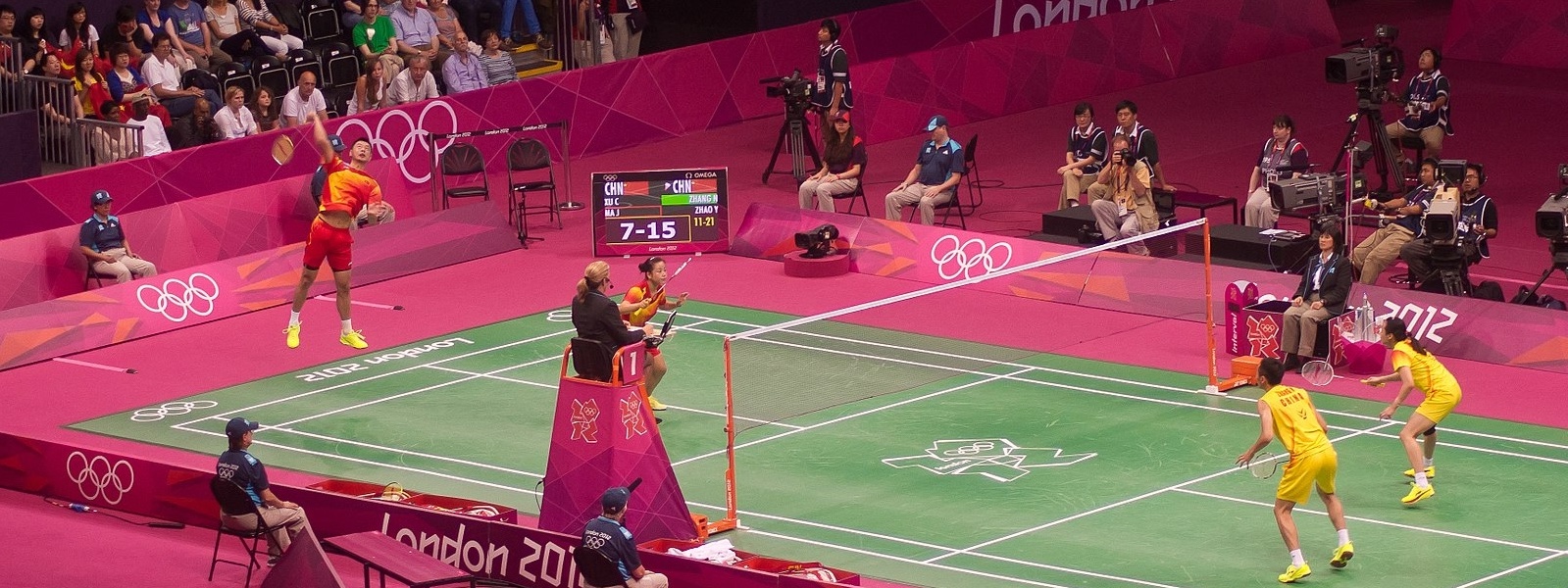 Mixed doubles badminton game at the 2012 London Olymipcs, with a guy about to smash.