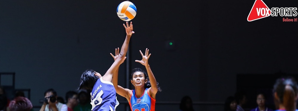 2 women jumping to both get the netball in the air.